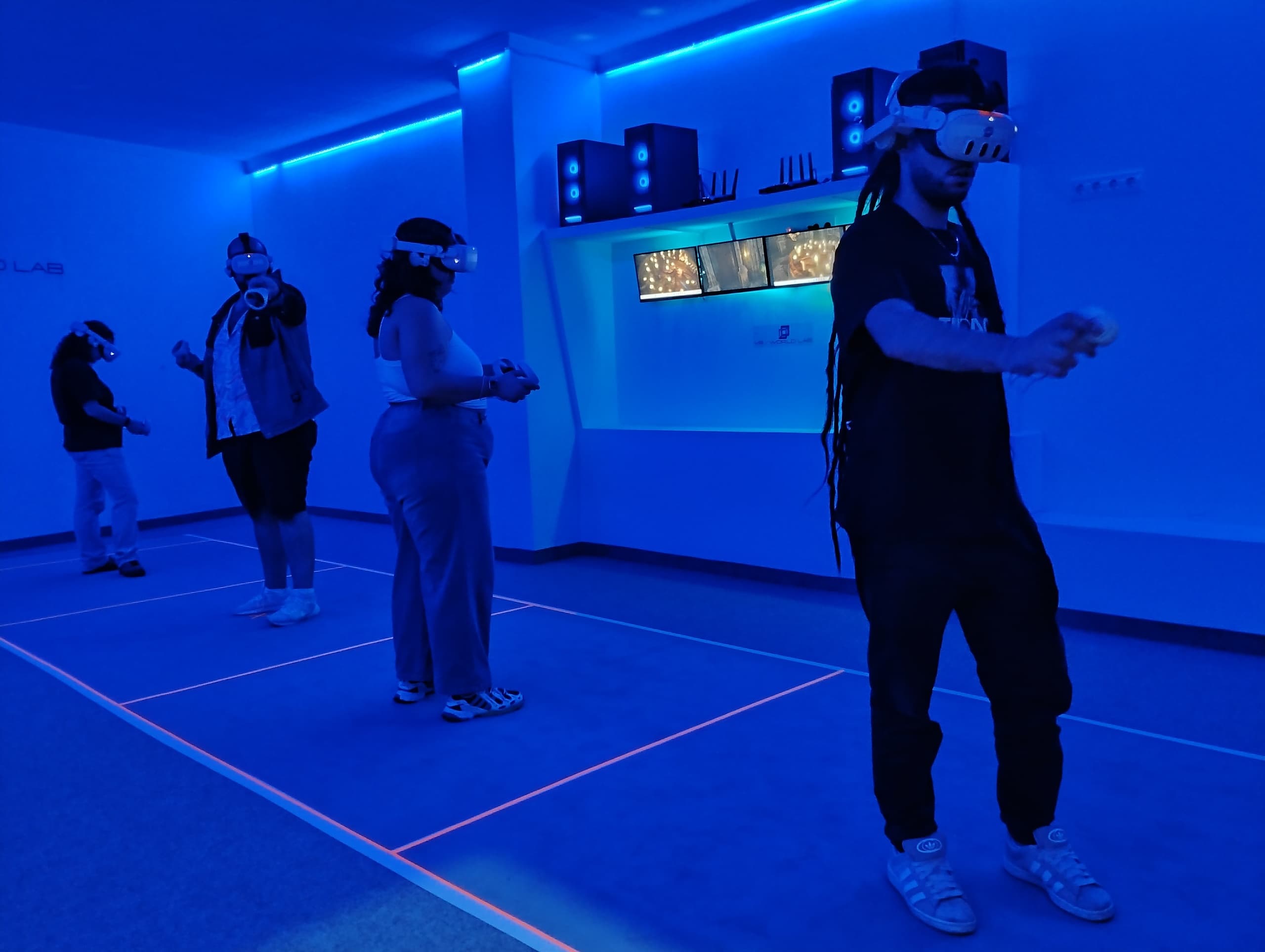 Group participating in VR multiplayer experience inside neon room