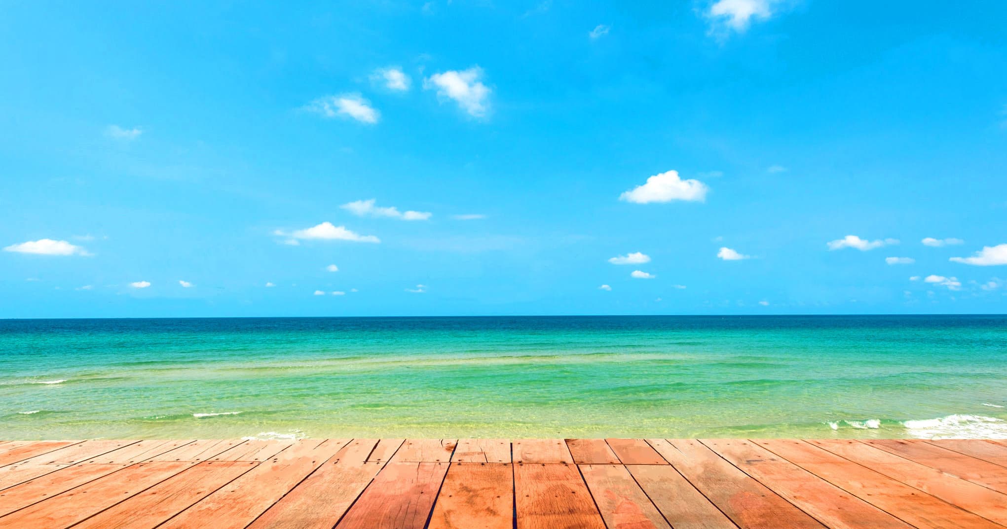 Wooden boardwalk overlooking turquoise sea and sunny tropical beach