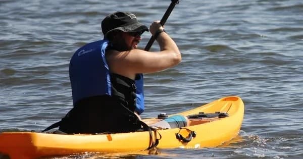 Kayaker paddling a yellow kayak on open lake waters, active touring