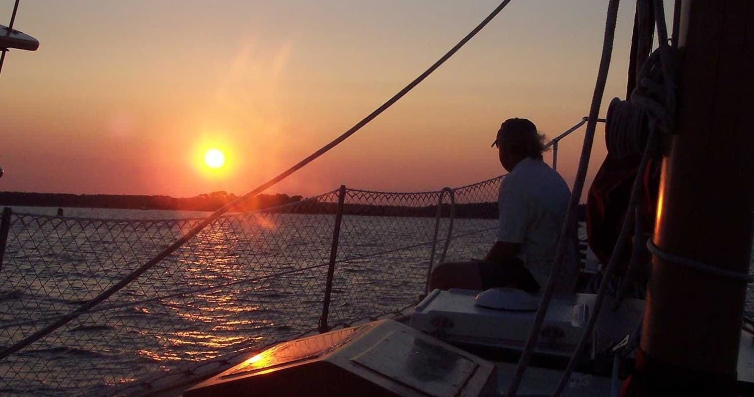 Sunset sailing cruise with captain at helm on calm waters