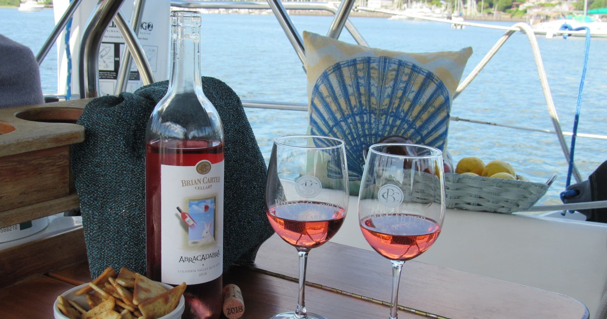 Rosé wine and glasses on sailboat table with harbor view
