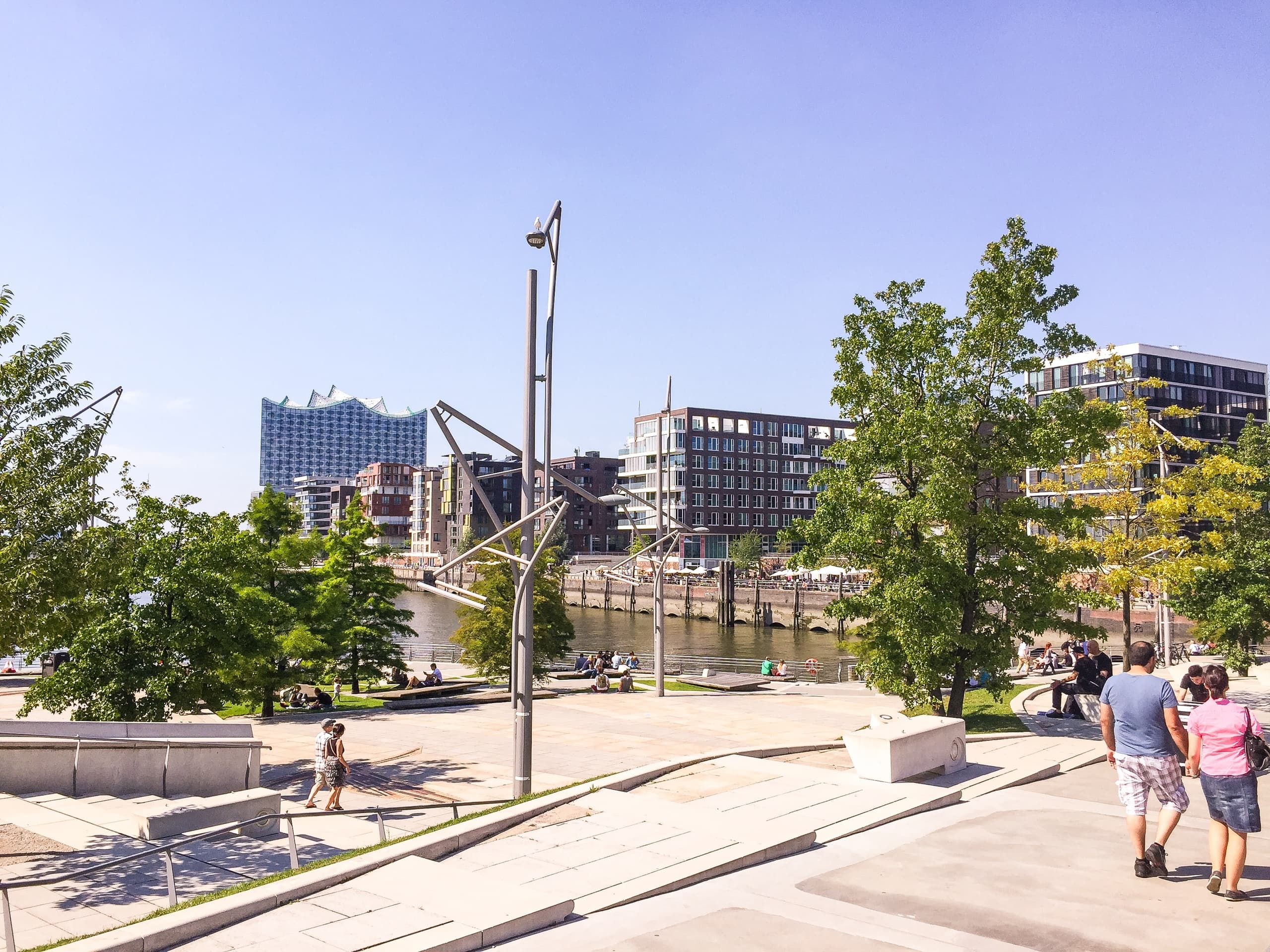 Couple walking along urban riverside promenade with city skyline