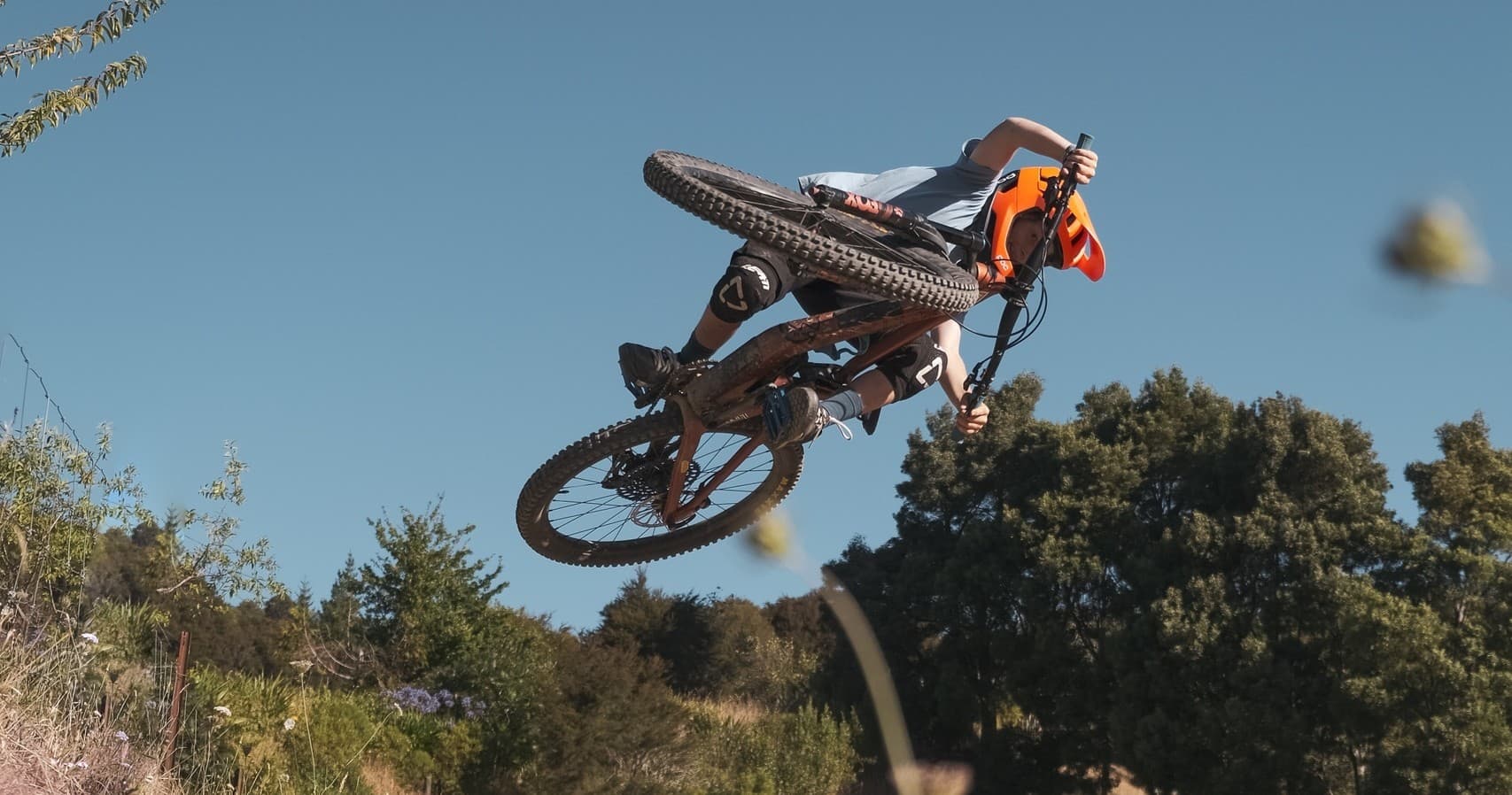 Mountain biker launching massive jump over dusty trail, Nelson