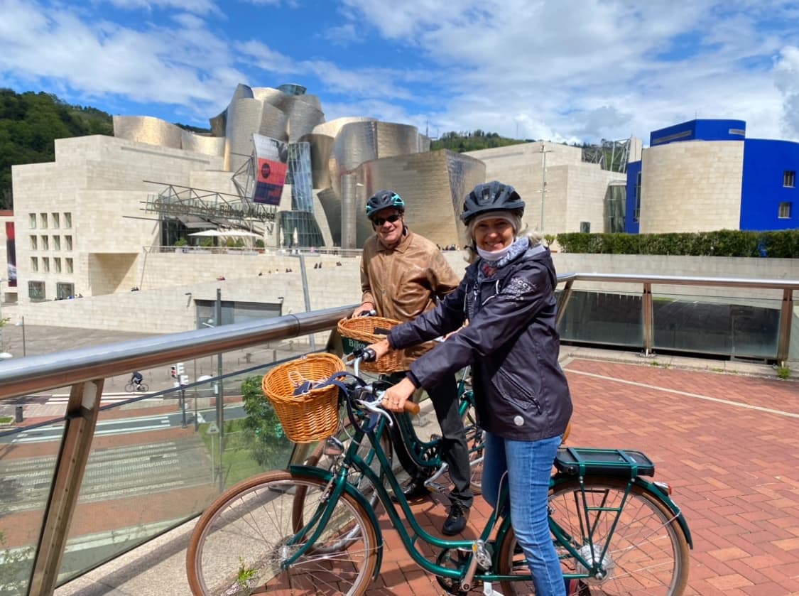 Couple on electric bikes in front of Guggenheim Bilbao museum