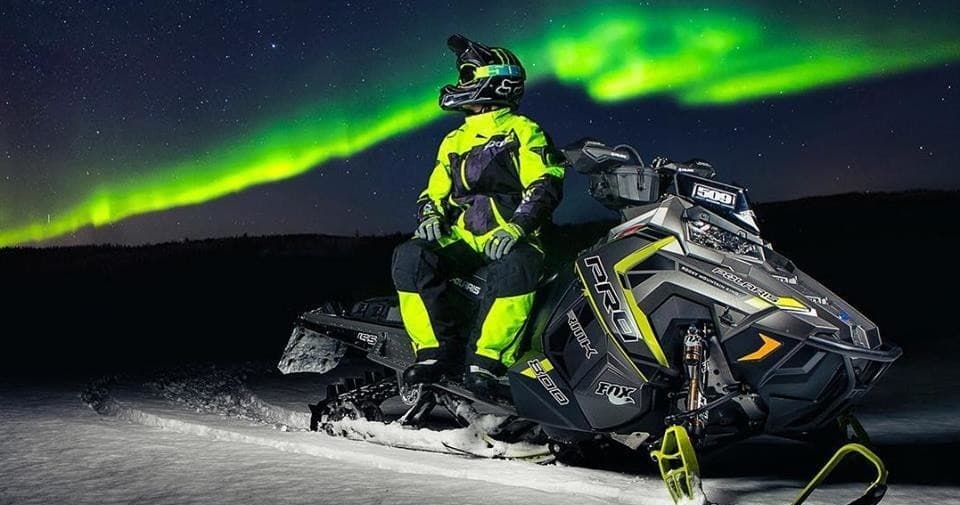 Snowmobile under aurora borealis on snowy Arctic night ride