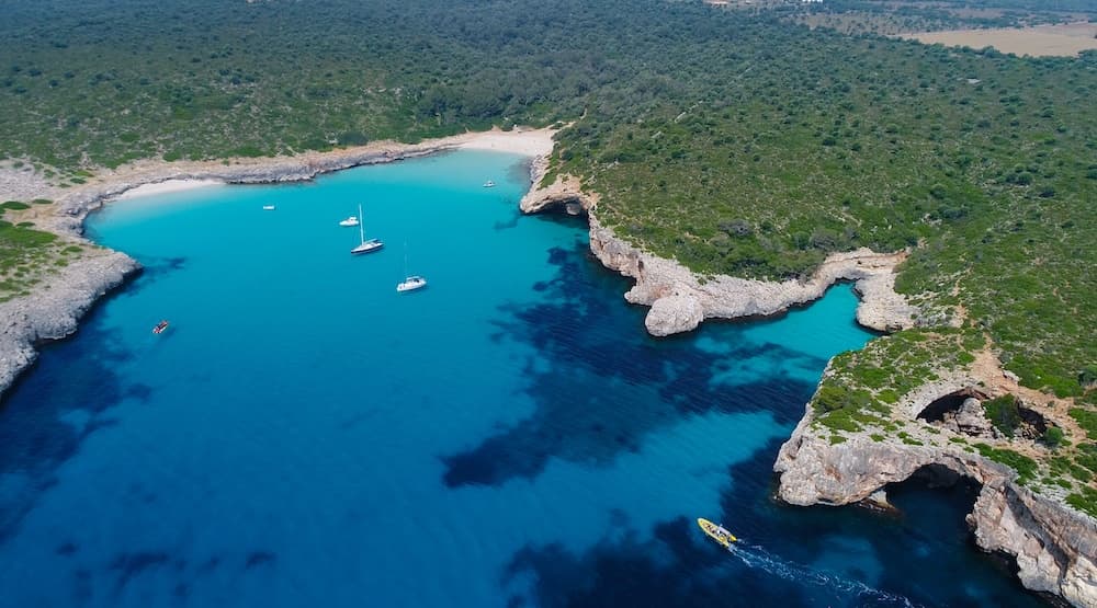 Aerial view of turquoise bay and sailboats on Mediterranean coast