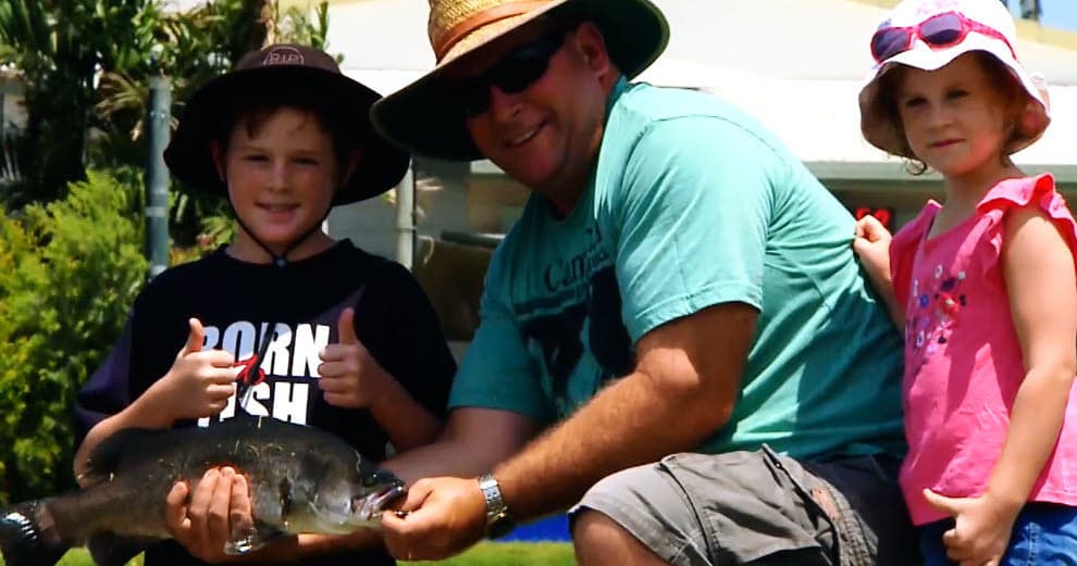 Family posing with caught fish at lakeside fishing spot