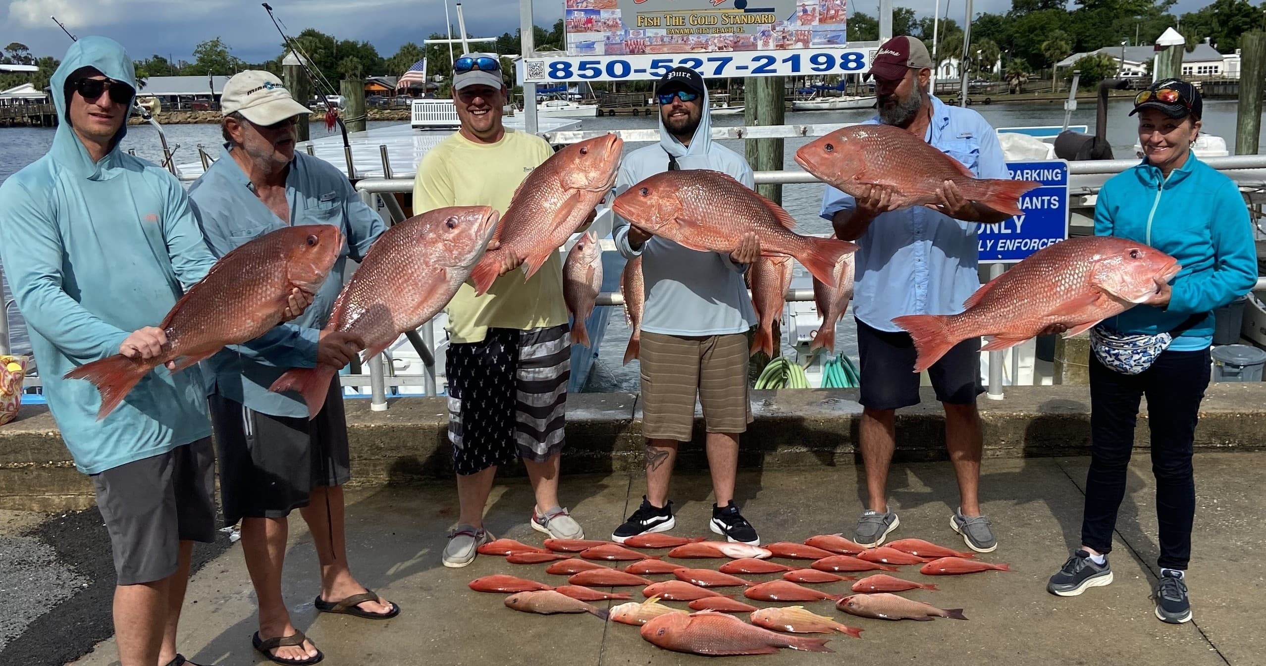 Anglers holding red snapper catch at marina, Gulf waters