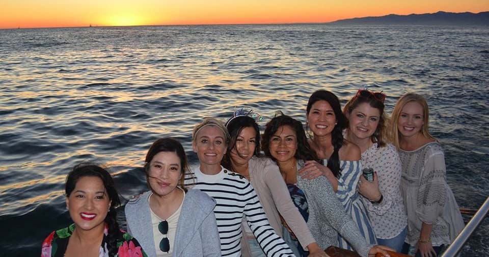 Sunset boat cruise with friends on calm ocean near coastline