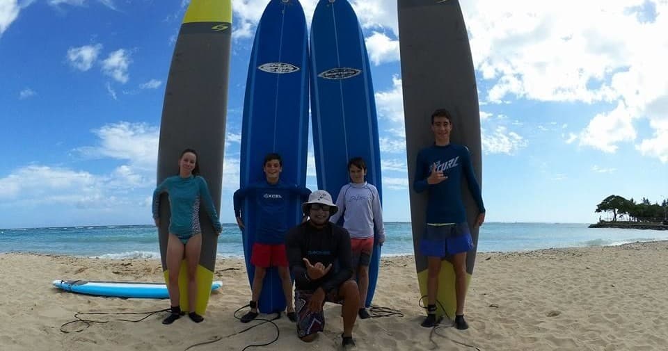 Group of surfers with longboards on sandy beach near ocean