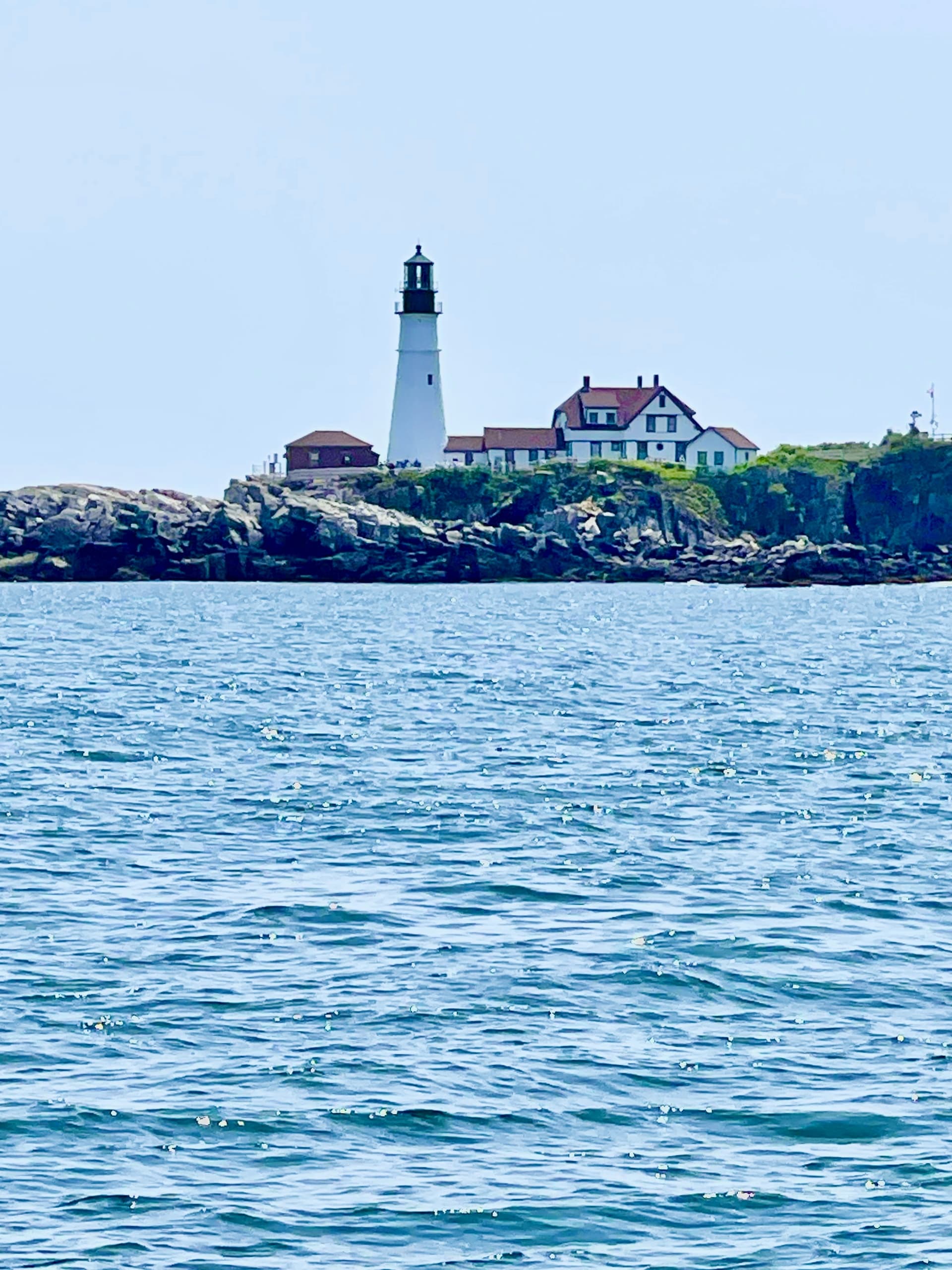 Lighthouse on rocky coast viewed across open ocean waters