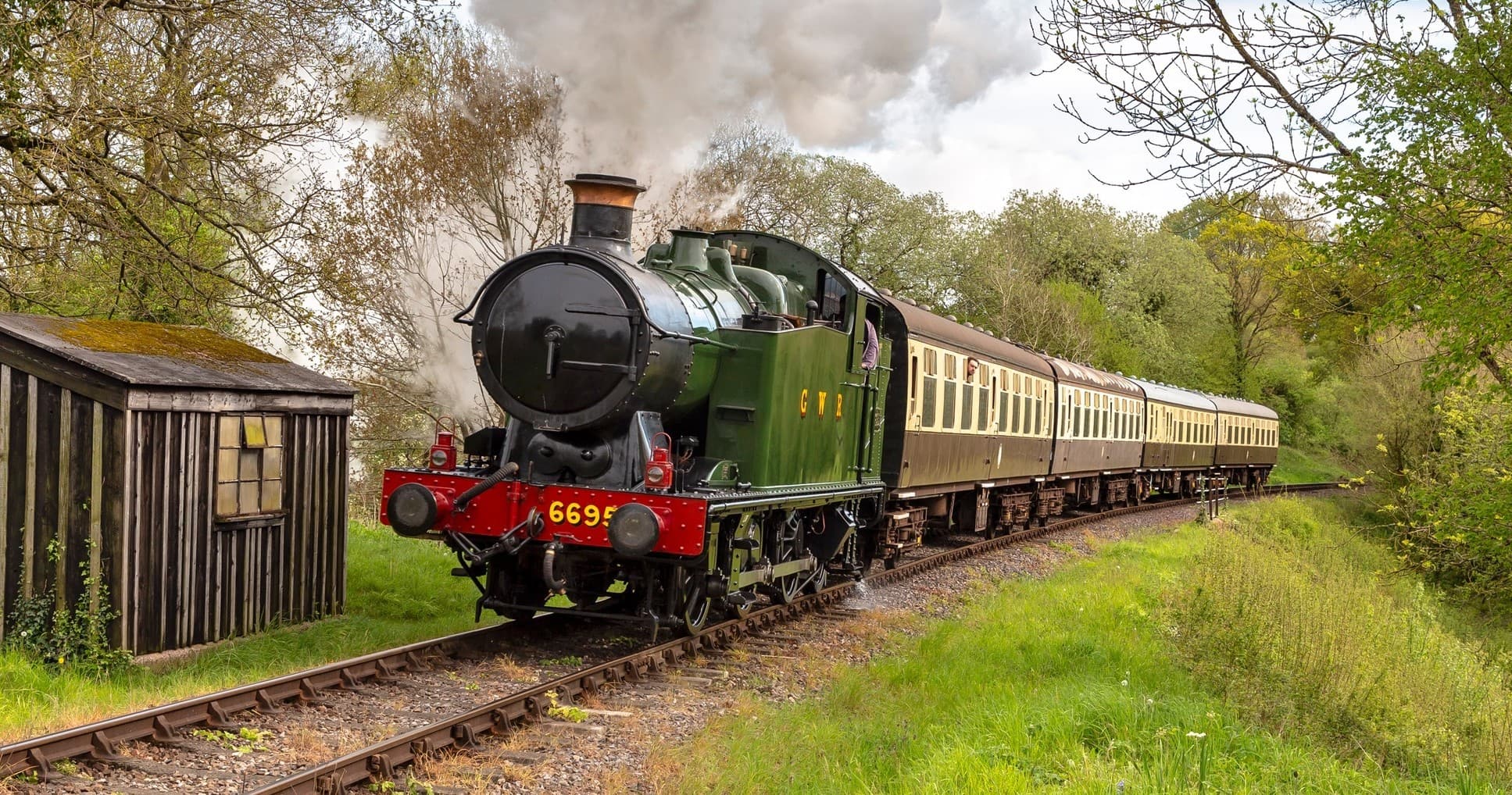 Green steam engine traveling scenic forested rural line
