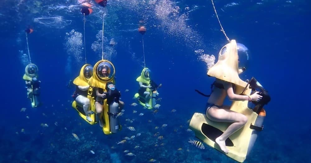 Helmet dive sea-walkers exploring Caribbean reef on underwater tour