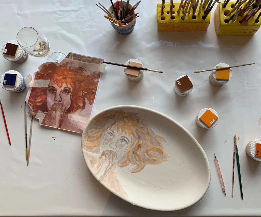 Painted ceramic plate portrait in pottery studio workspace