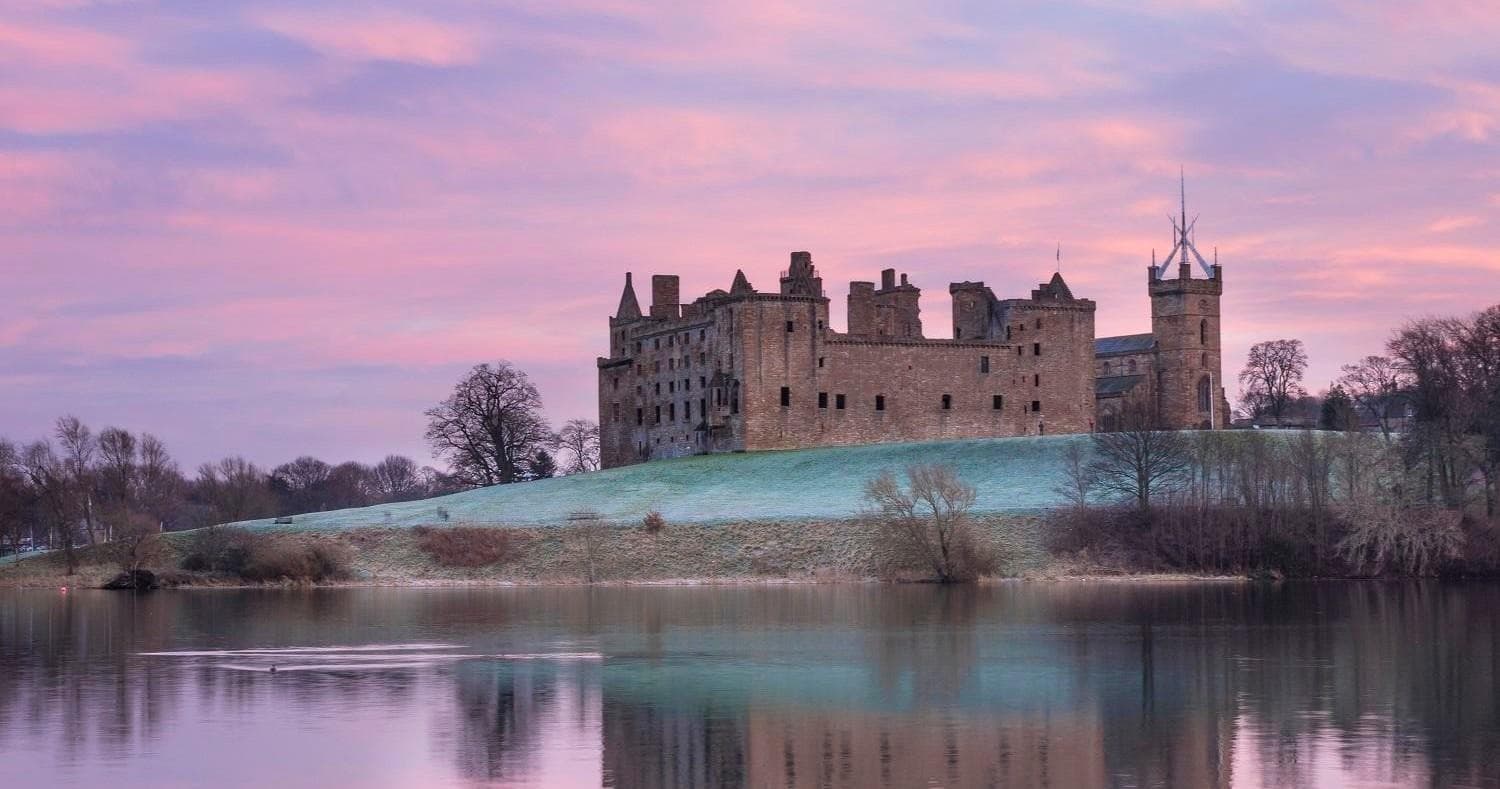 Historic lakeside castle at sunrise with reflective calm waters