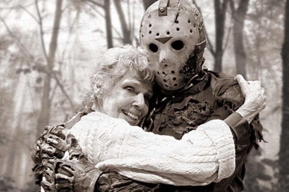 Masked scare actor hugging visitor in wooded outdoor haunt scene