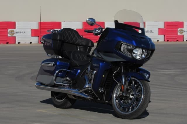 Blue touring motorcycle staged in paved lot near red barriers