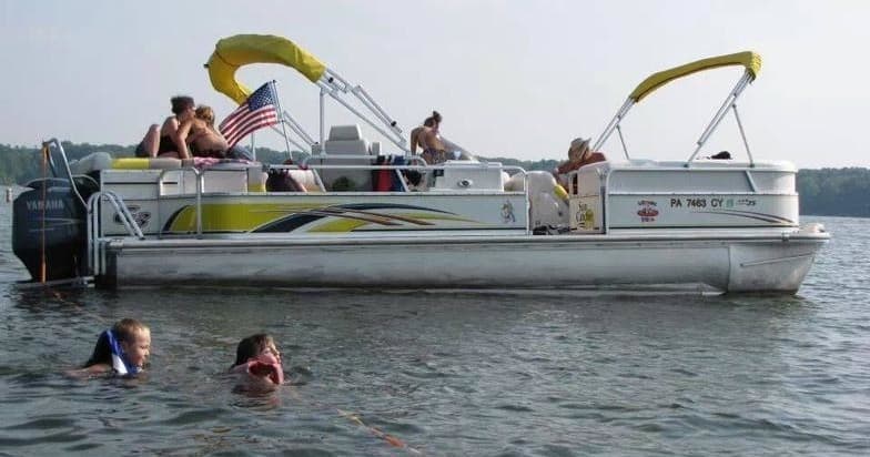 Family on pontoon boat with swimmers enjoying open lake waters