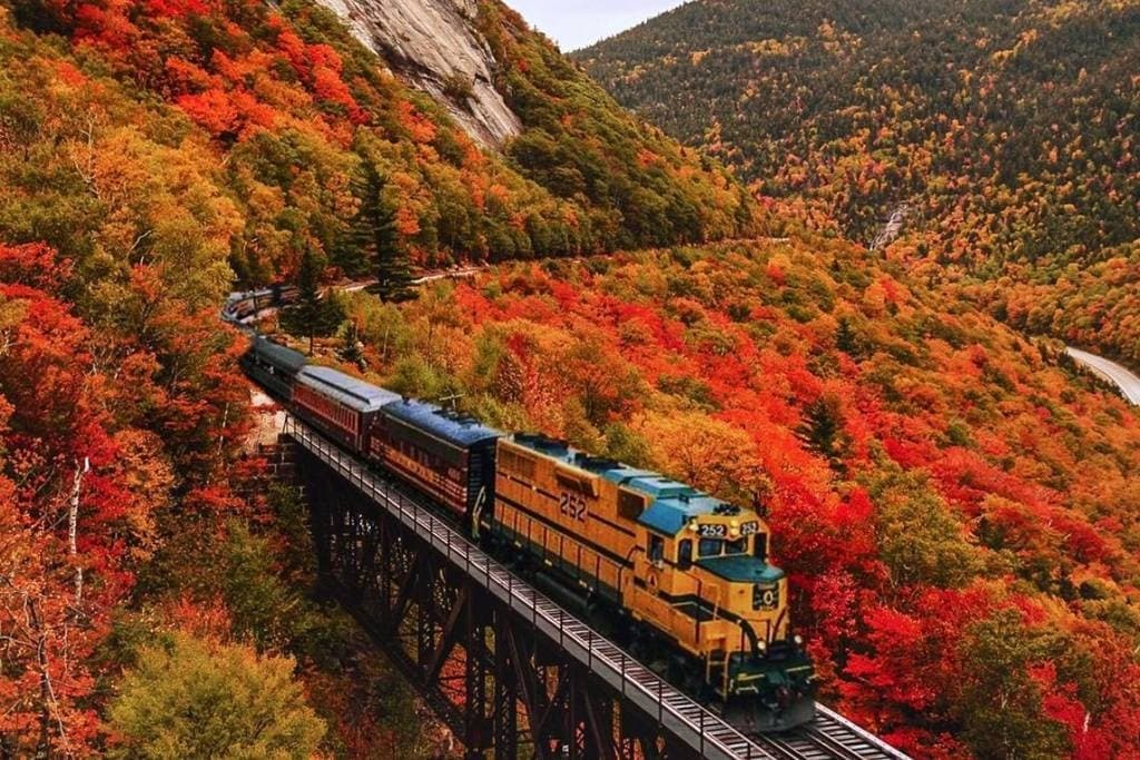 Train winding through autumn mountains with vibrant fall foliage