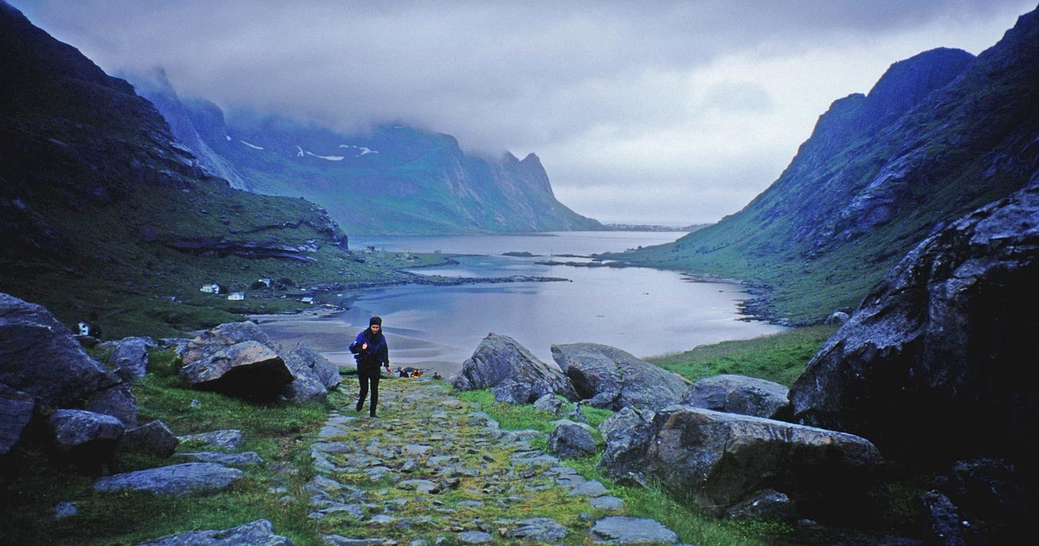 Hiker walking toward scenic mountain fjord valley at dawn