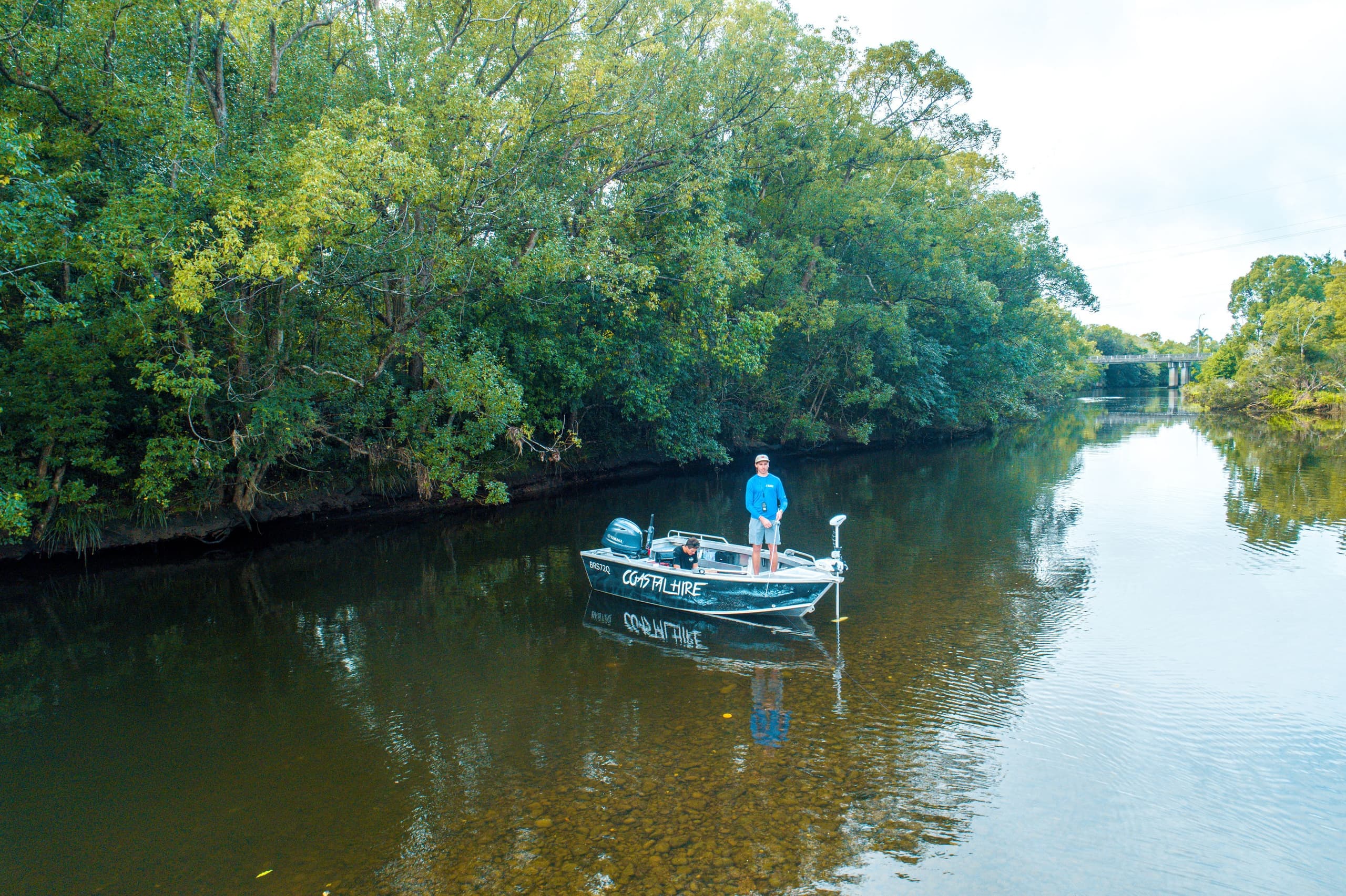 Angler on boat drifting in calm mangrove river, scenic fishing trip