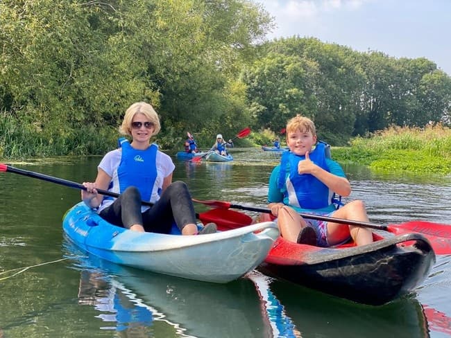 Two smiling kayakers enjoying calm river paddle in scenic countryside