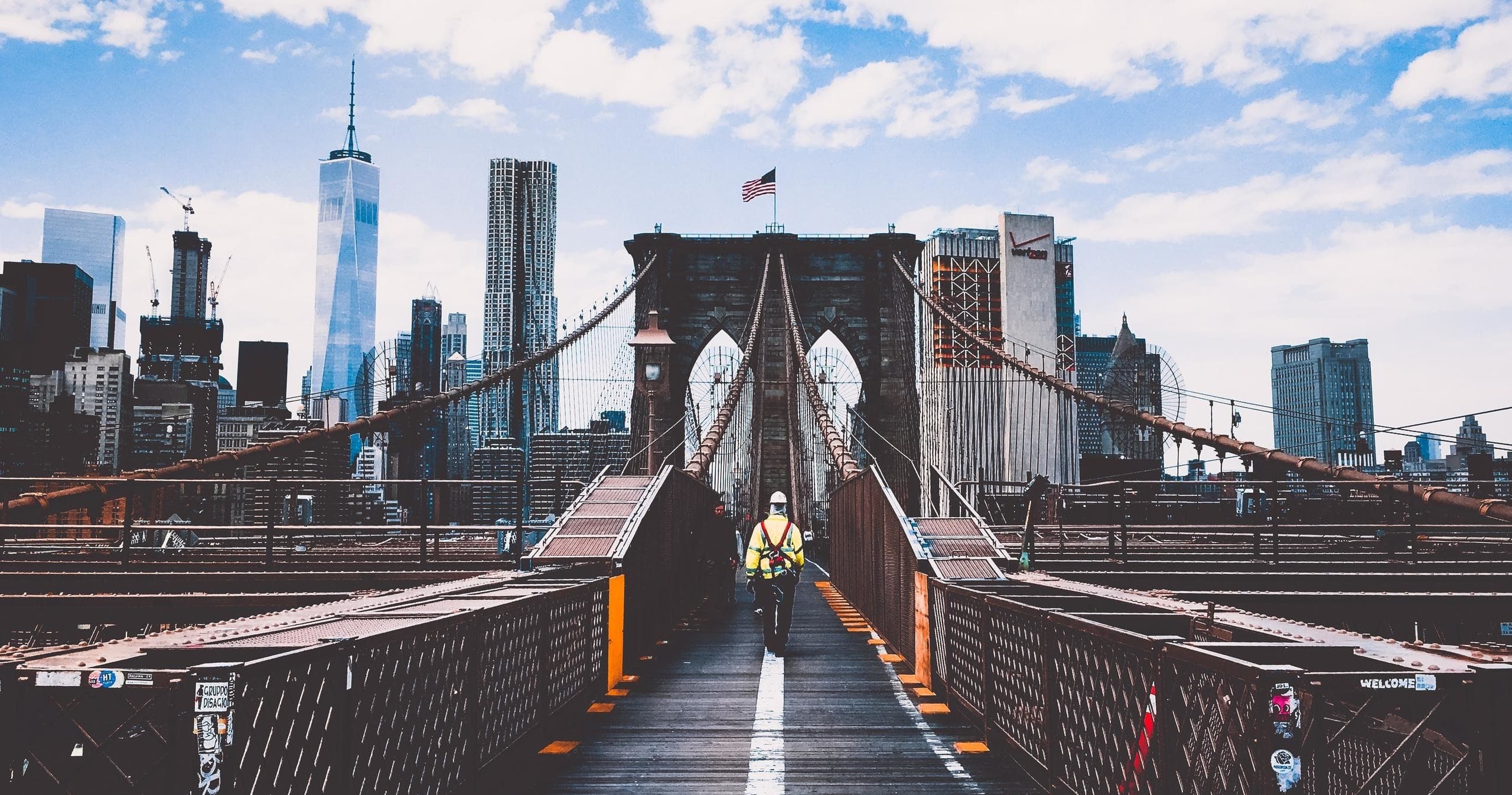 Pedestrians walking across Brooklyn Bridge with Manhattan skyline