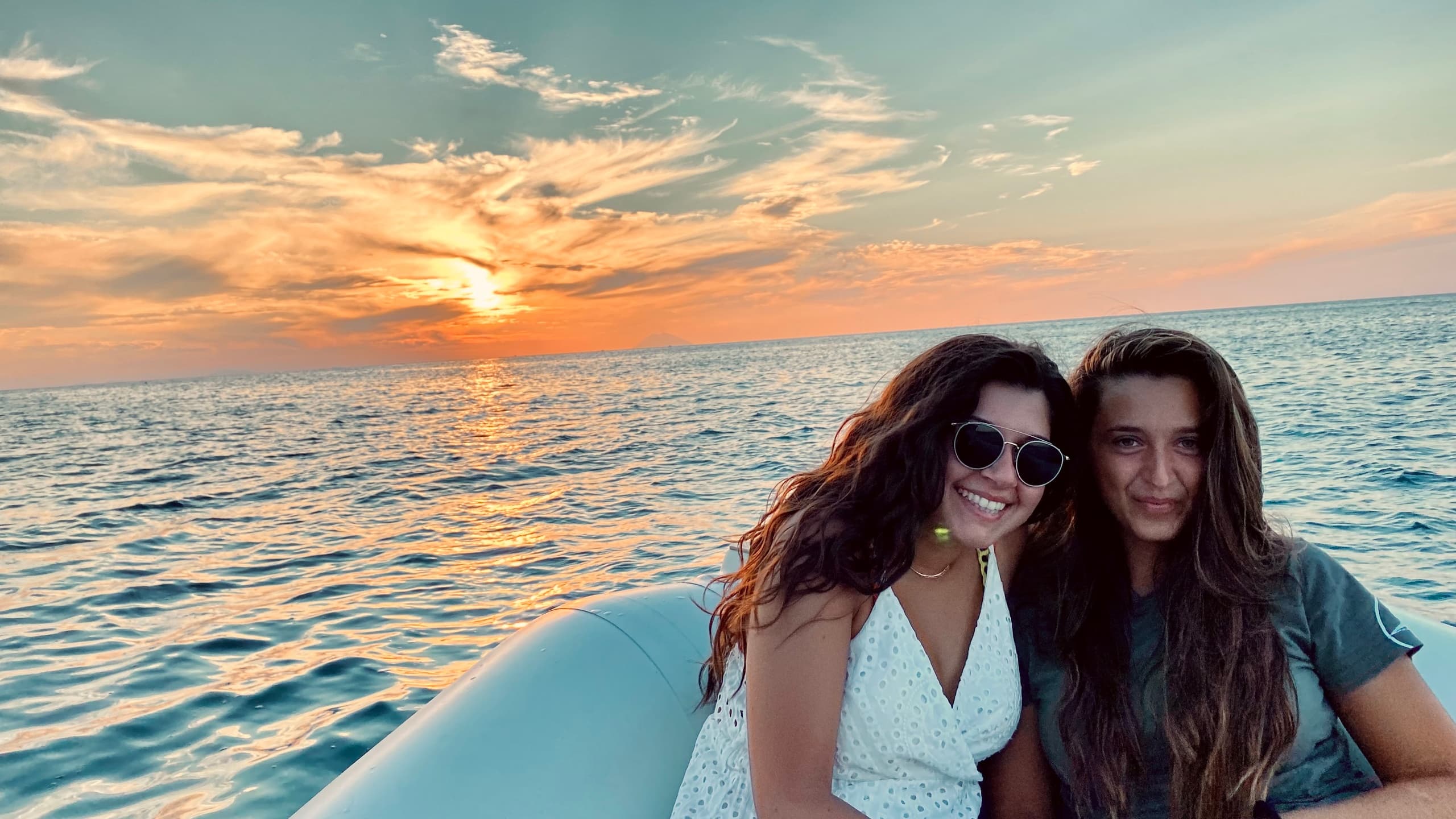 Two women on boat at sunset off Mediterranean coast