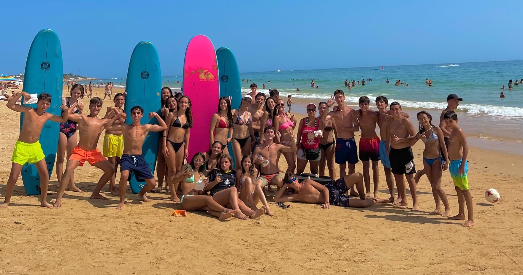 Group surf lesson on sunny sandy beach with colorful surfboards