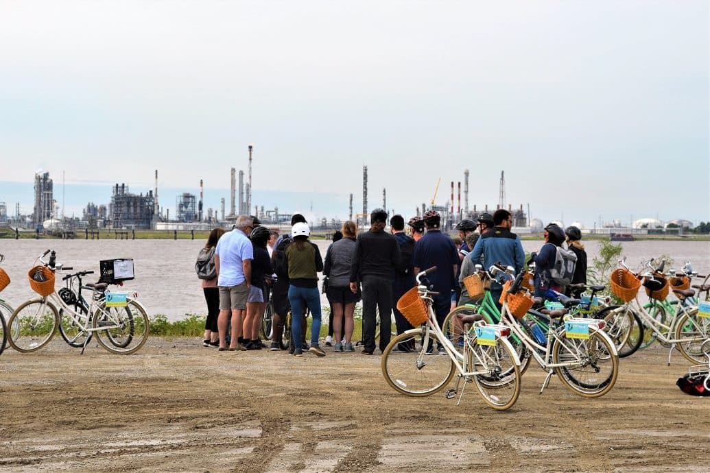 Group cyclists on a waterfront bike tour viewing industrial skyline