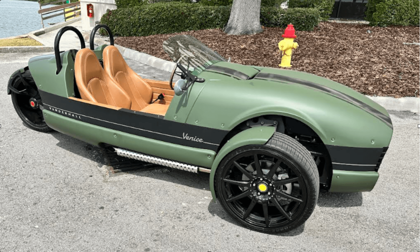 Green retro three-wheeler parked by waterfront park path