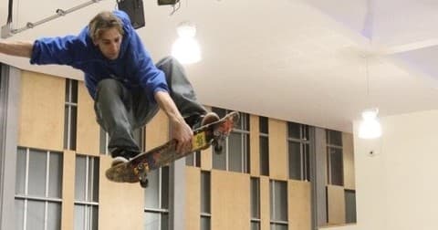 Skateboarder mid-air performing a trick inside an indoor skatepark