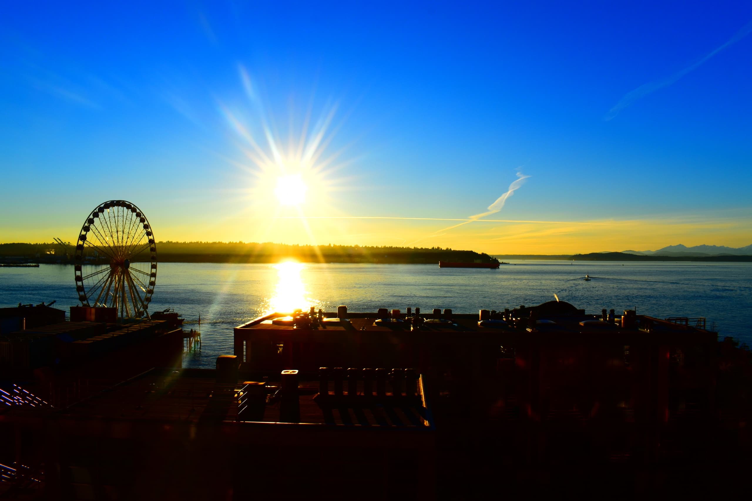 Sunrise over waterfront ferris wheel with glowing sunburst view