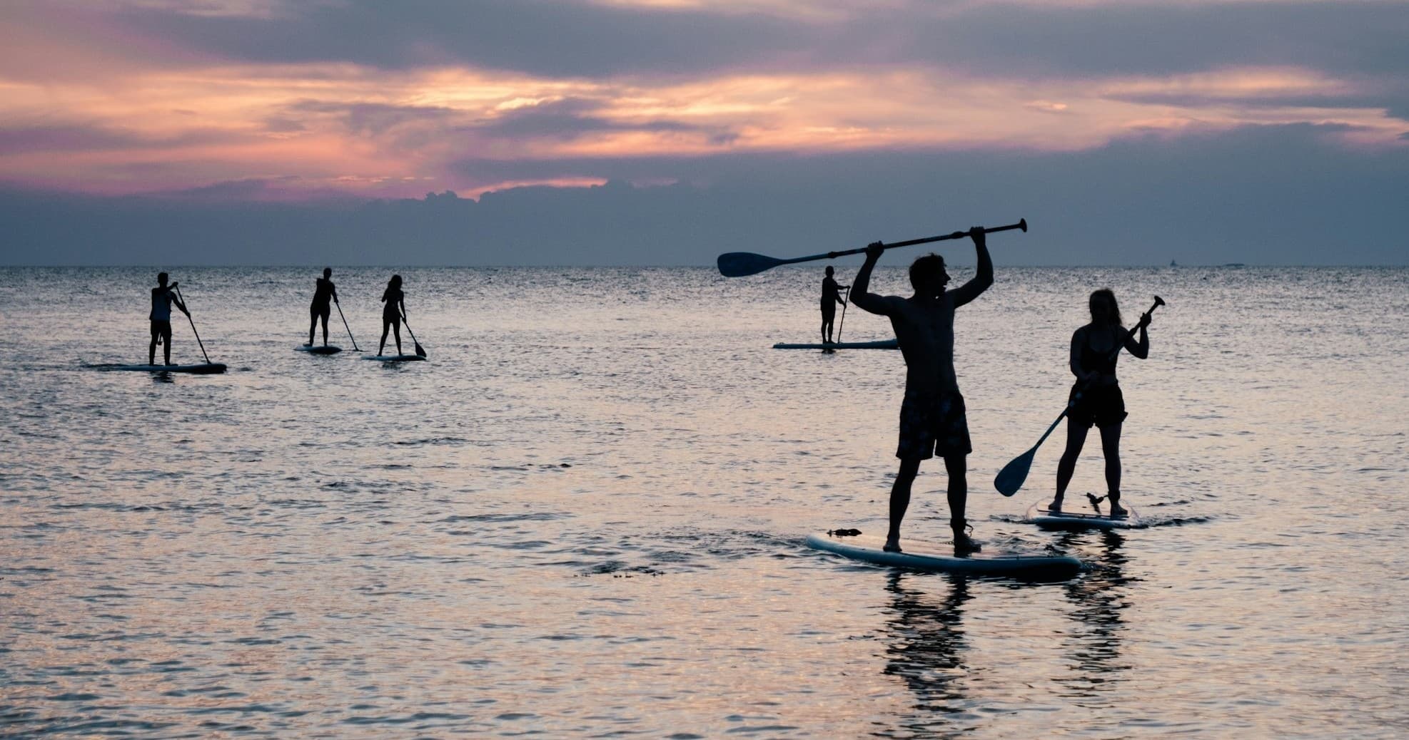Stand up paddleboarders silhouetted at Biloxi beach sunset