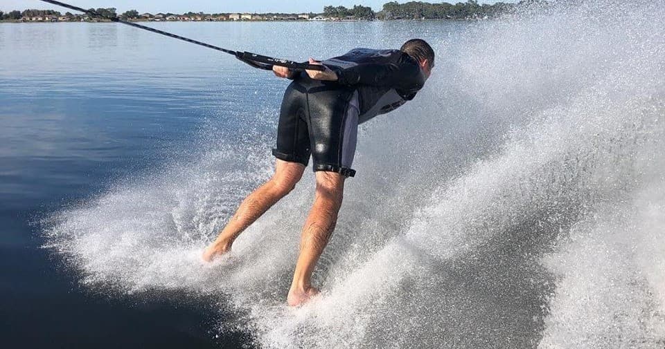 Athlete barefoot waterskiing carving a turn with high water spray