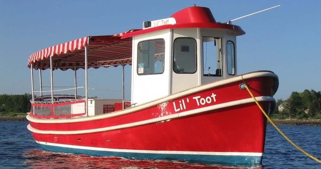 Red sightseeing tour boat Lil Toot on calm coastal bay waters
