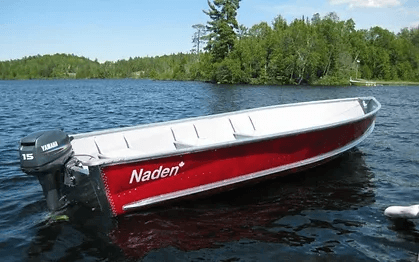 Red aluminum motorboat anchored on calm lake near trees