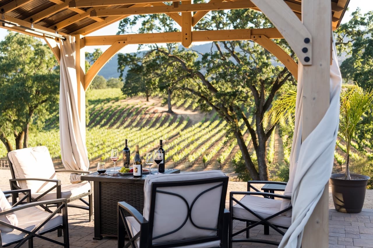 Outdoor tasting patio overlooking vineyard rows, relaxed seating