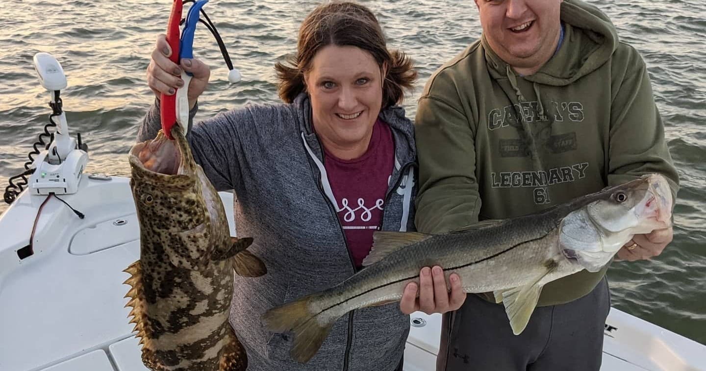 Couple displaying mixed catches aboard boat in coastal waters