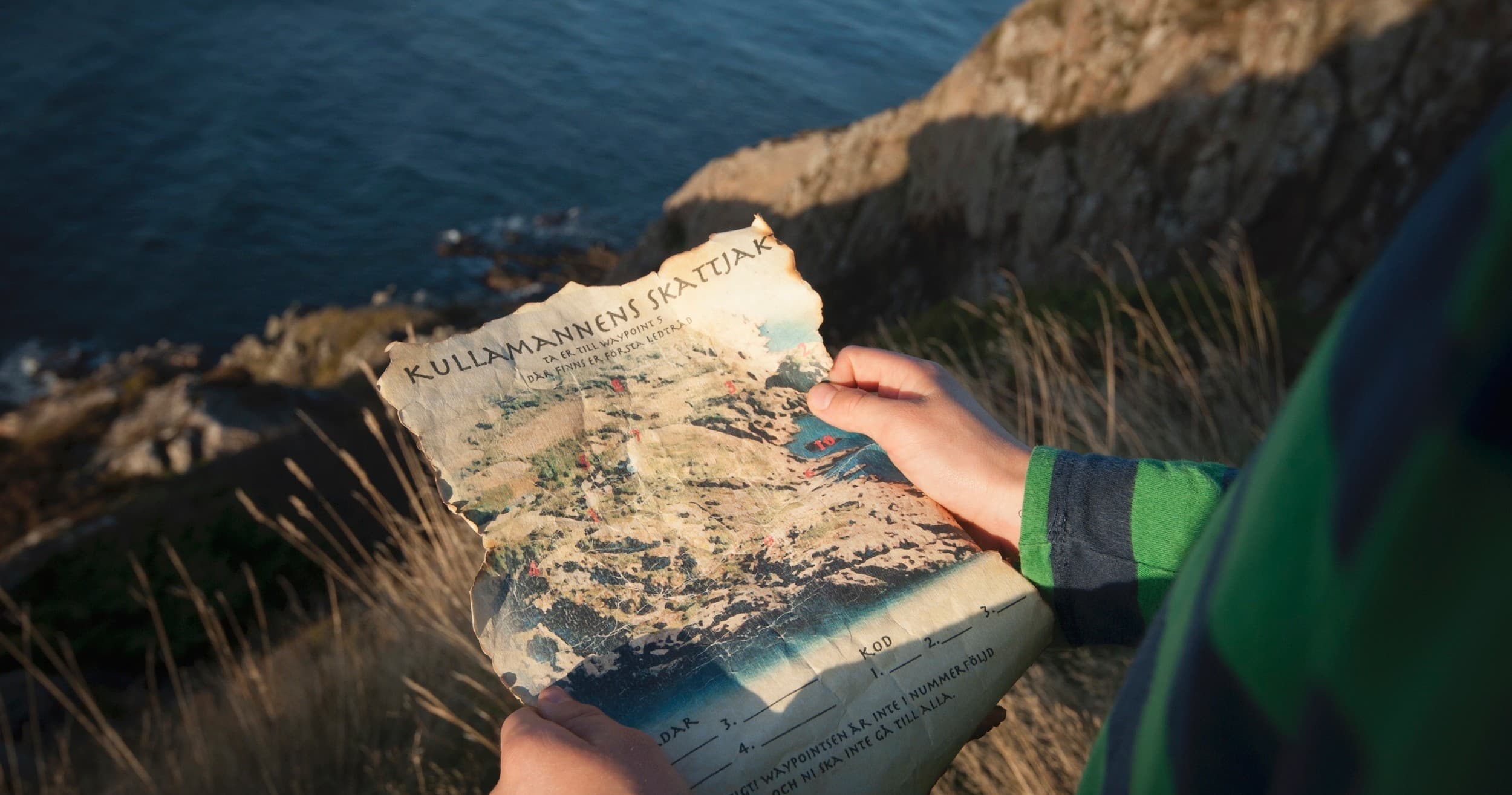 Traveler reading map on seaside cliff overlooking rugged coast