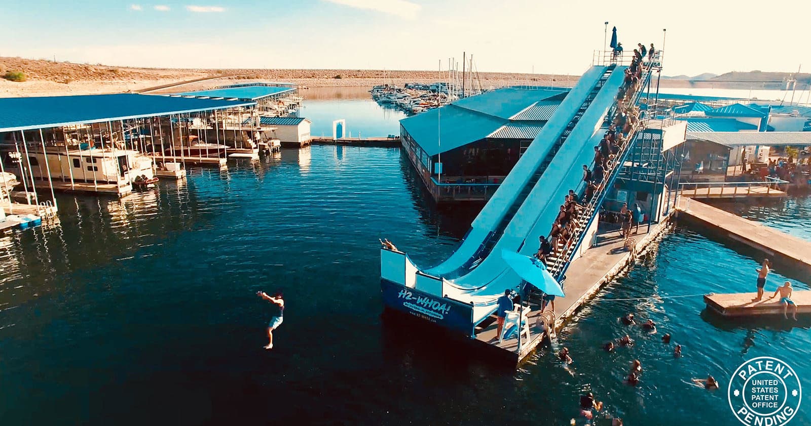 Aerial view of lake slide platform with people jumping into water