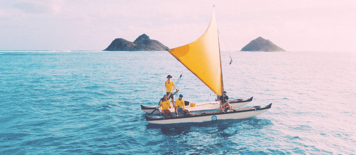 Traditional sailing outrigger with yellow sail on calm turquoise sea
