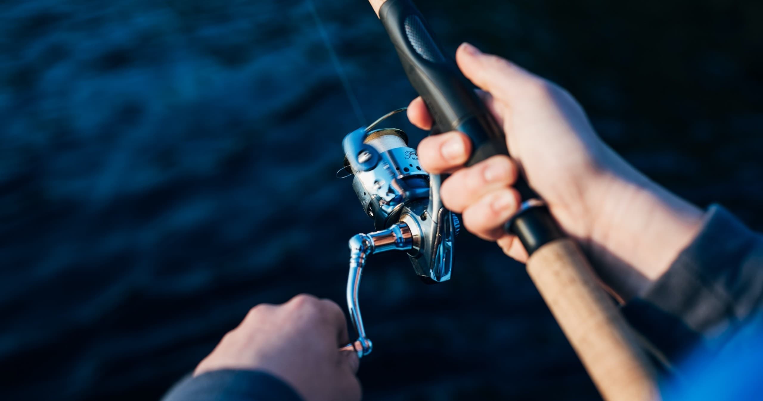Hands reeling rod while fishing offshore on deep blue water