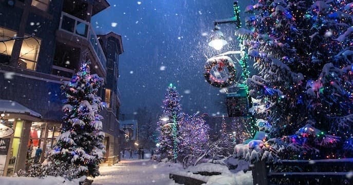 Snowy village street with holiday lights and festive decorations