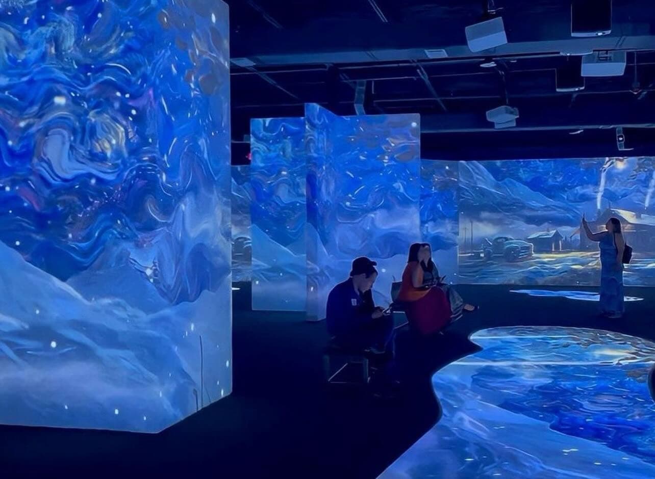 Immersive digital art projections in indoor gallery, visitors viewing