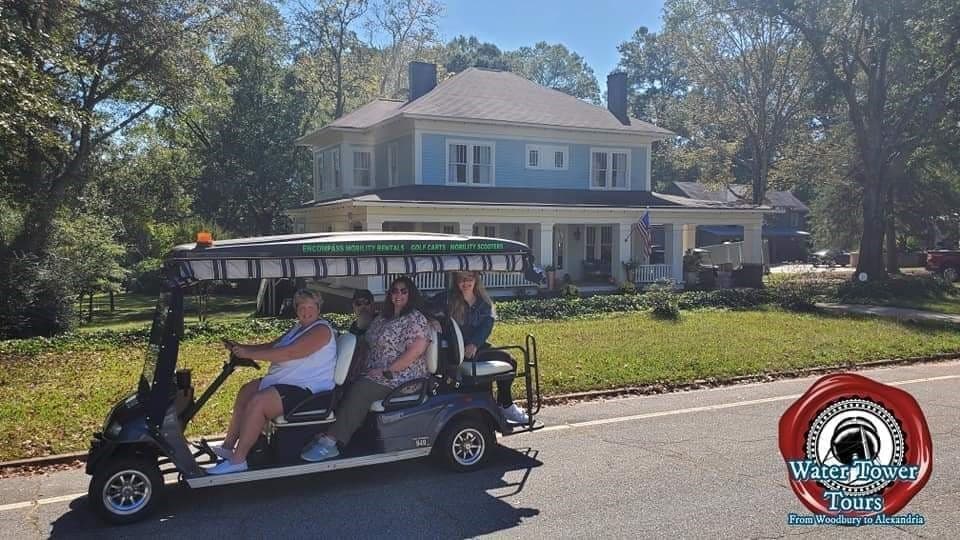 Golf-cart sightseeing tour past historic waterfront homes on sunny street