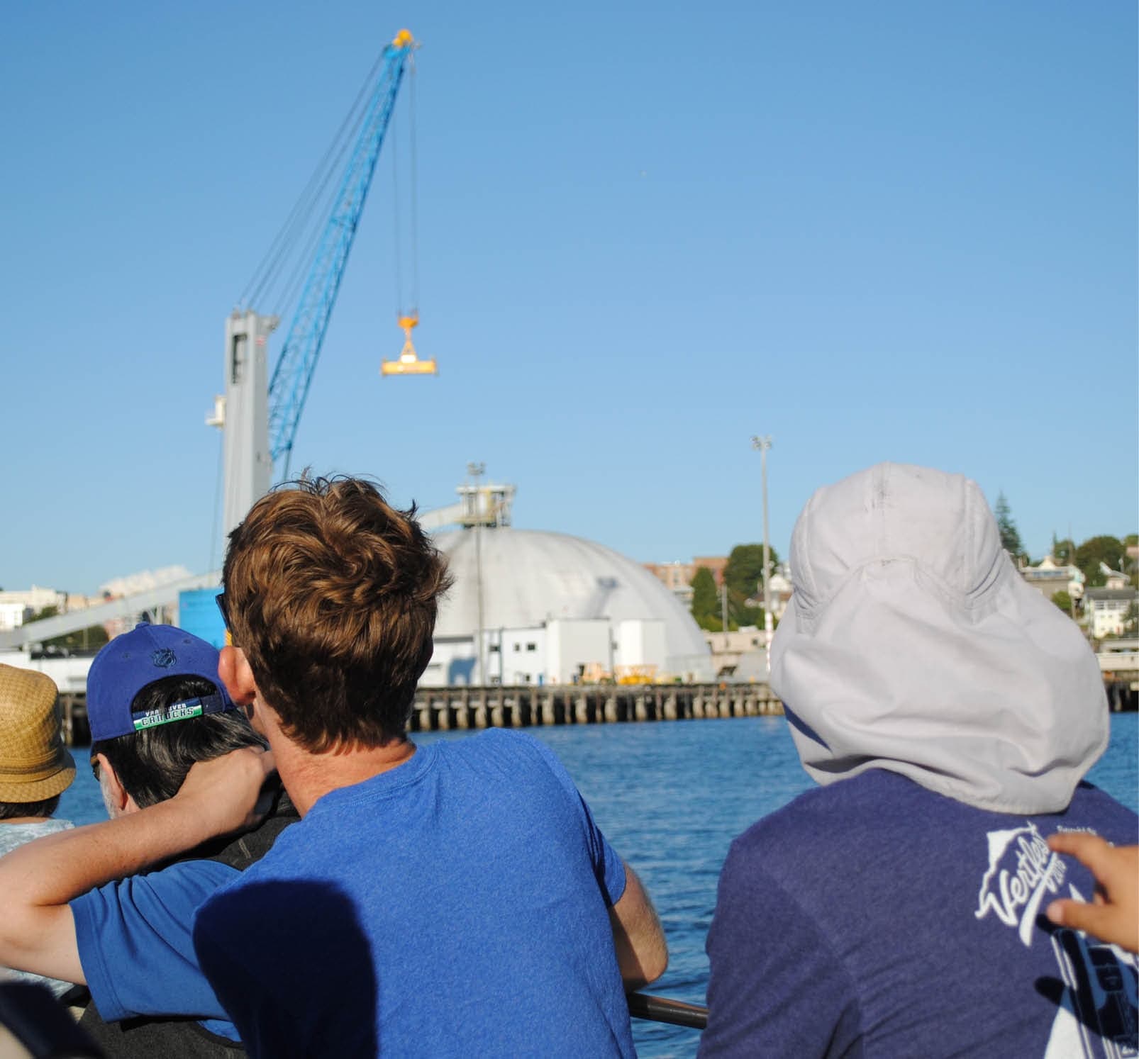 Sightseers on boat looking toward industrial harbor and crane