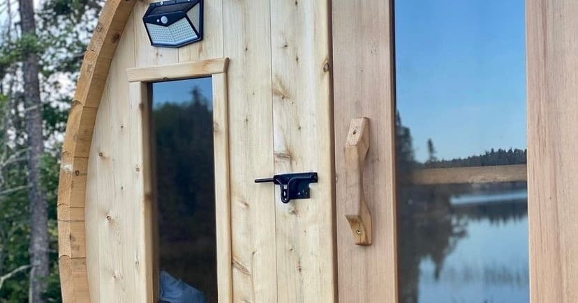 Close-up of barrel sauna door with lakeside reflection and handle