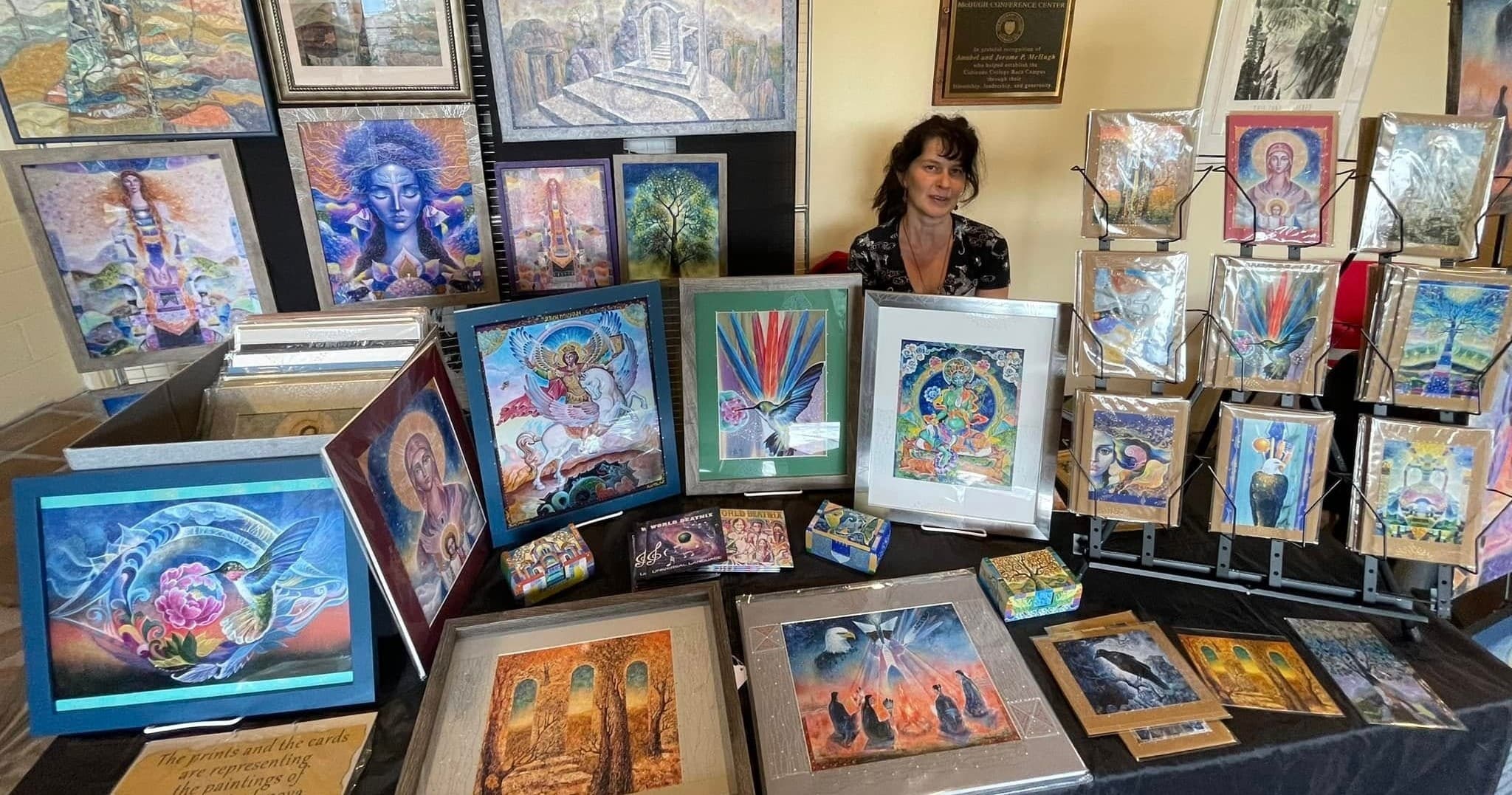 Table of framed mystical artworks displayed at indoor art fair