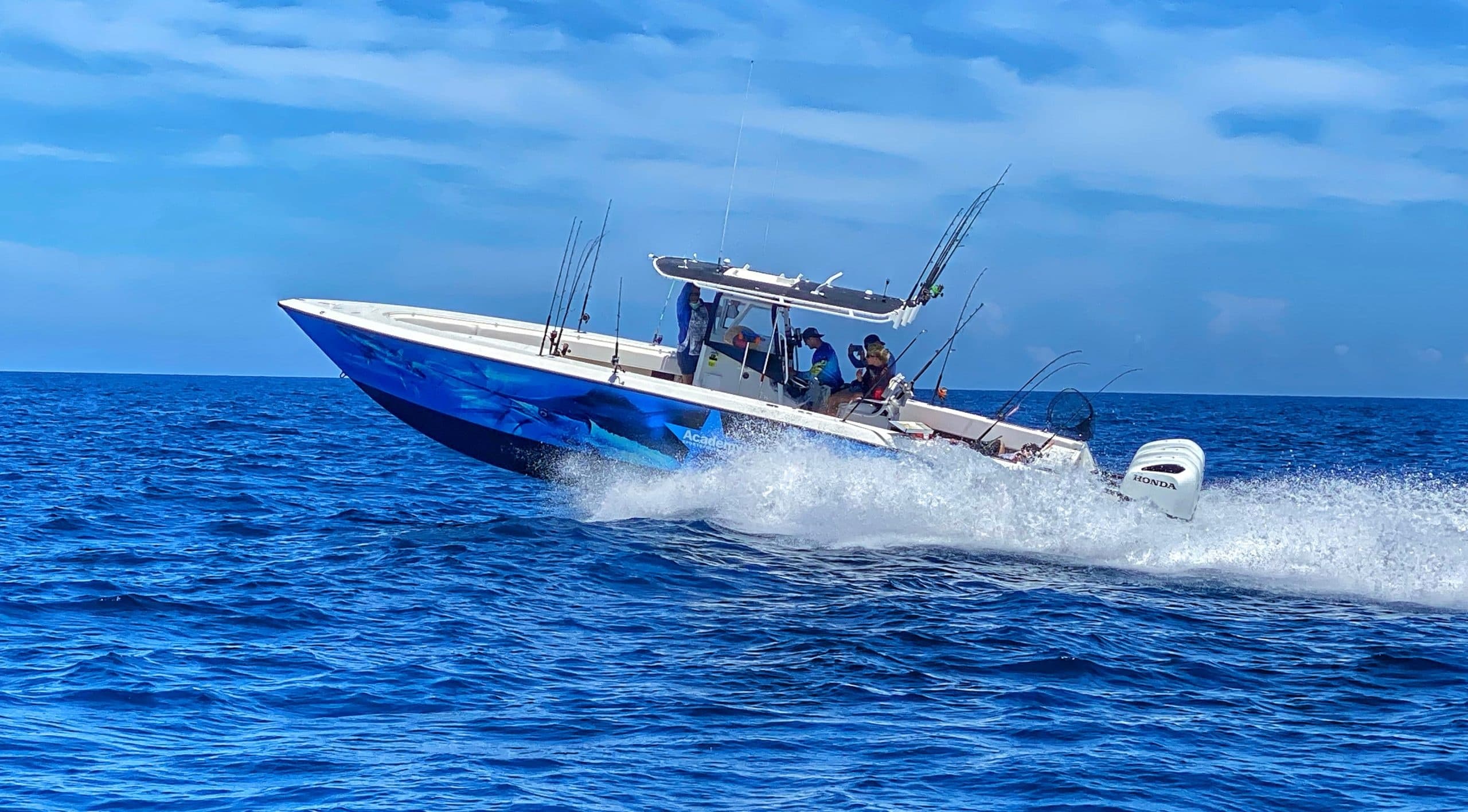 Blue sportfishing boat slicing waves with crew preparing tackle gear